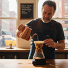 Barista brewing coffee in sunlit café