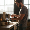 Young man making espresso in sunlit kitchen