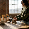 Woman arranging specialty coffee gift sets in loft