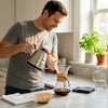 Person making pour-over coffee in bright kitchen
